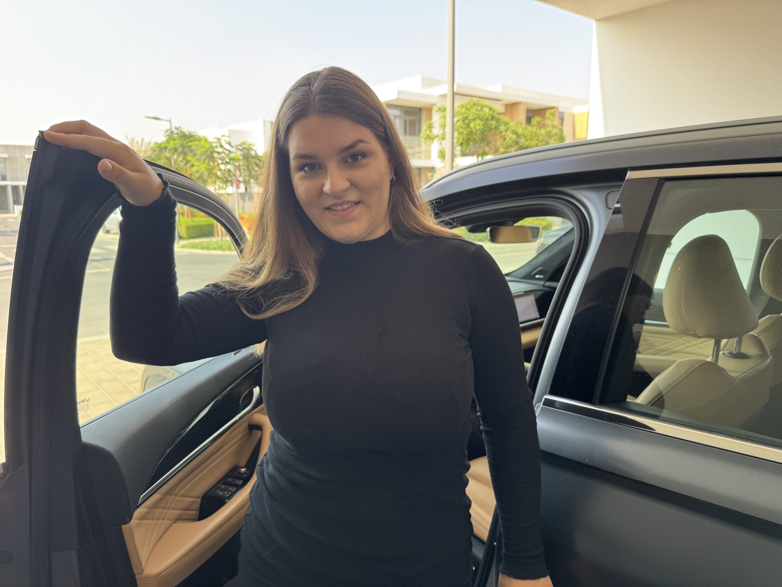 Unternehmerin im schwarzen Kleid steigt aus SUV – moderner Business-Lifestyle mit Selbstbewusstsein